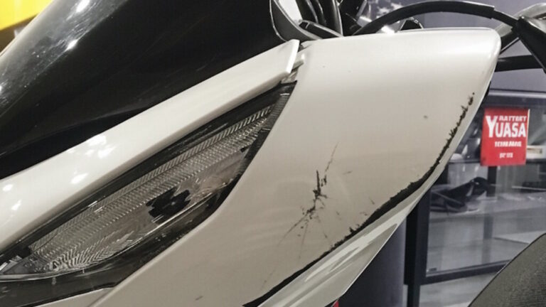 Motocicleta blanca con daños visibles en el lateral