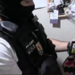 Agente de policía mostrando utensilios relacionados con drogas en un local