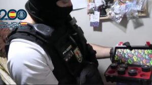 Agente de polic&iacute;a mostrando utensilios relacionados con drogas en un local