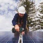 T&eacute;cnico instalando paneles solares en un edificio bajo un cielo nublado