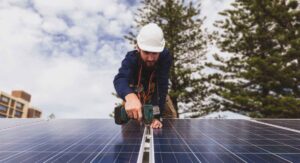 T&eacute;cnico instalando paneles solares en un edificio bajo un cielo nublado