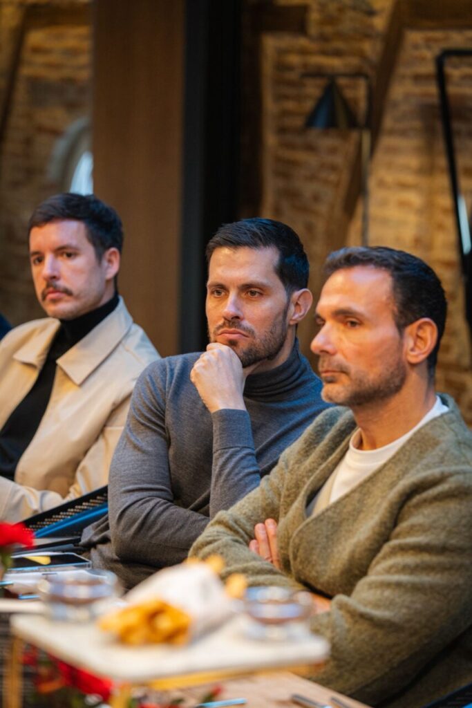 Tres hombres sentados en una mesa durante un evento de lectura en Madrid.