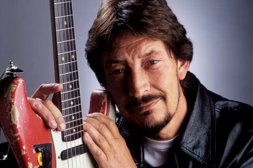 Chris Rea posando con una guitarra el&eacute;ctrica en un fondo neutro