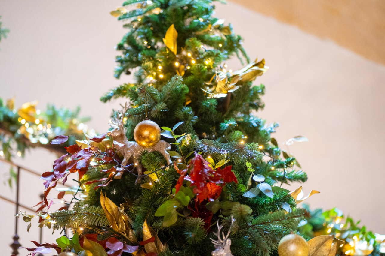 &Aacute;rbol de Navidad decorado con luces y lazos en tonos dorados y naturales