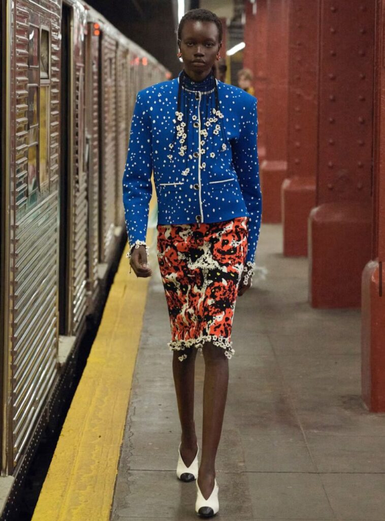 Modelo caminando en una estación de metro con un traje de Chanel.