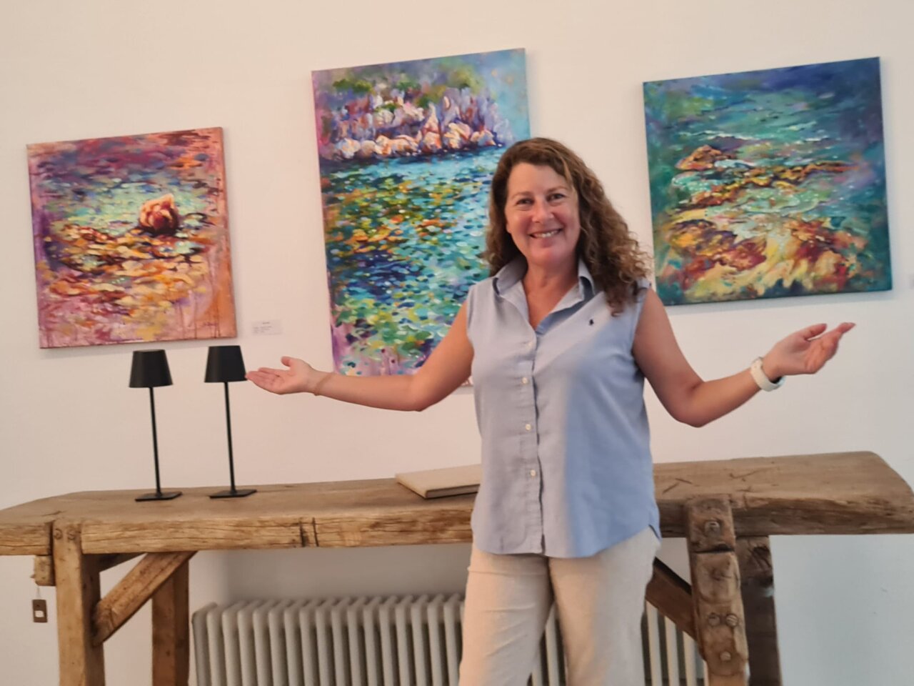 Dolors Martí en su estudio con obras de arte coloridas.