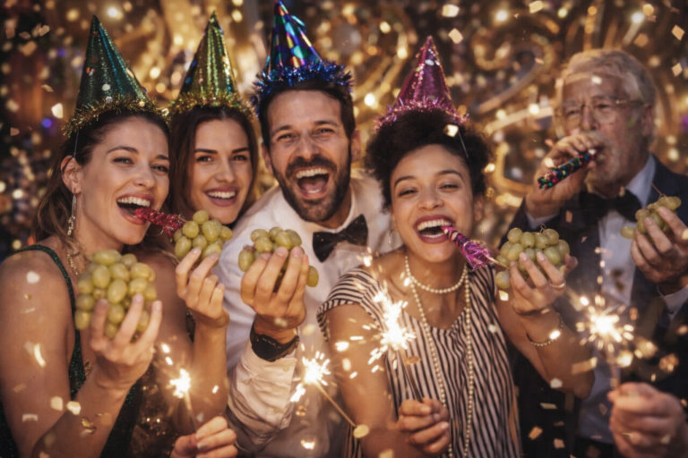 Grupo de personas celebrando con uvas y confeti en Nochevieja
