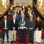 Grupo de personas posando en un escenario con un trofeo