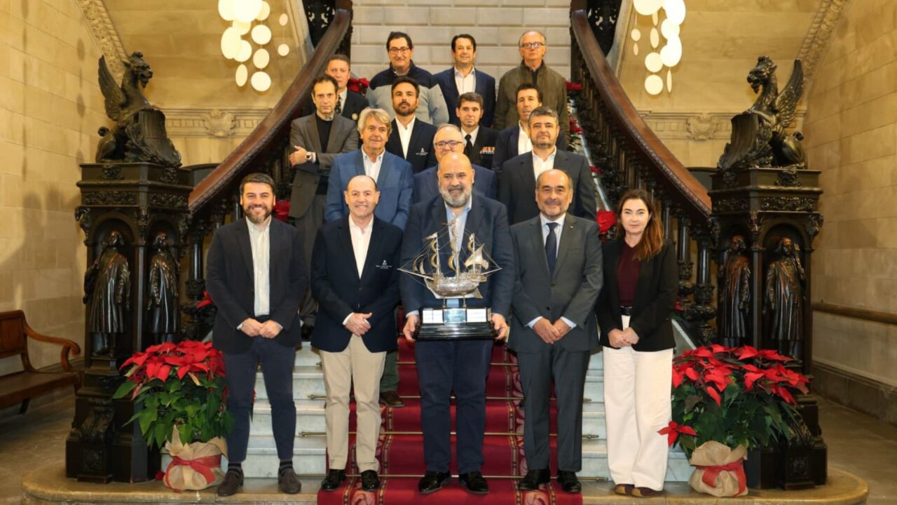 Grupo de personas posando en un escenario con un trofeo