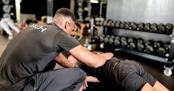 Entrenador asistiendo a un deportista en un gimnasio moderno