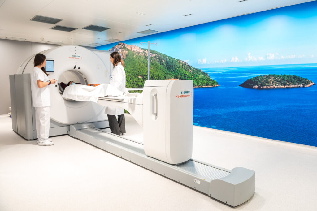 Dos profesionales de la salud junto a un escáner Siemens en un entorno clínico