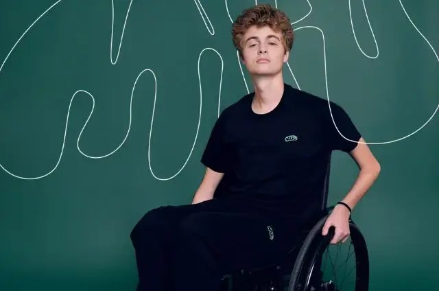 Joven en silla de ruedas posando con fondo verde