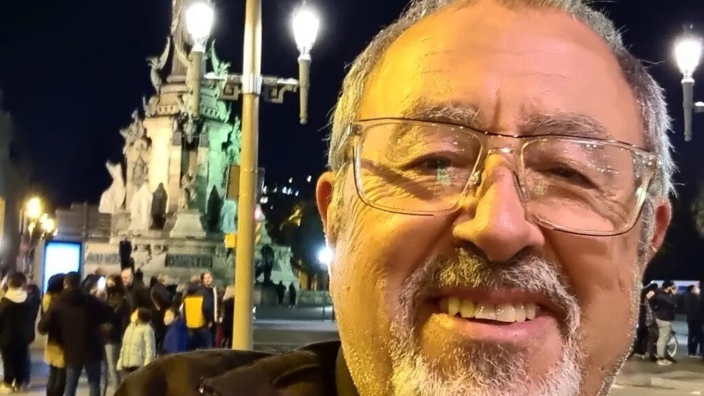 Hombre sonriendo en una plaza iluminada por farolas