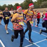 Participantes corriendo en la Hidrobal Sant Silvestre Calvianera con gorros navide&ntilde;os.