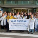 Médicos en huelga sosteniendo un cartel en la entrada de un hospital