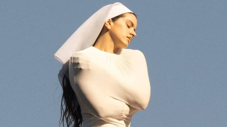 Rosalía en una pose artística con un fondo azul claro