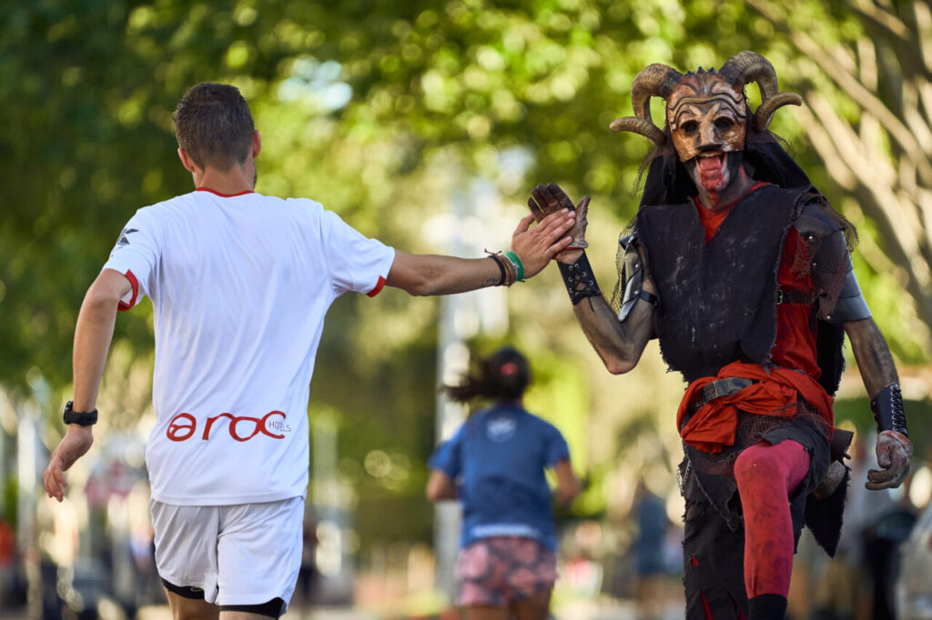 Corredor en Magaluf saludando a un personaje disfrazado durante la carrera.