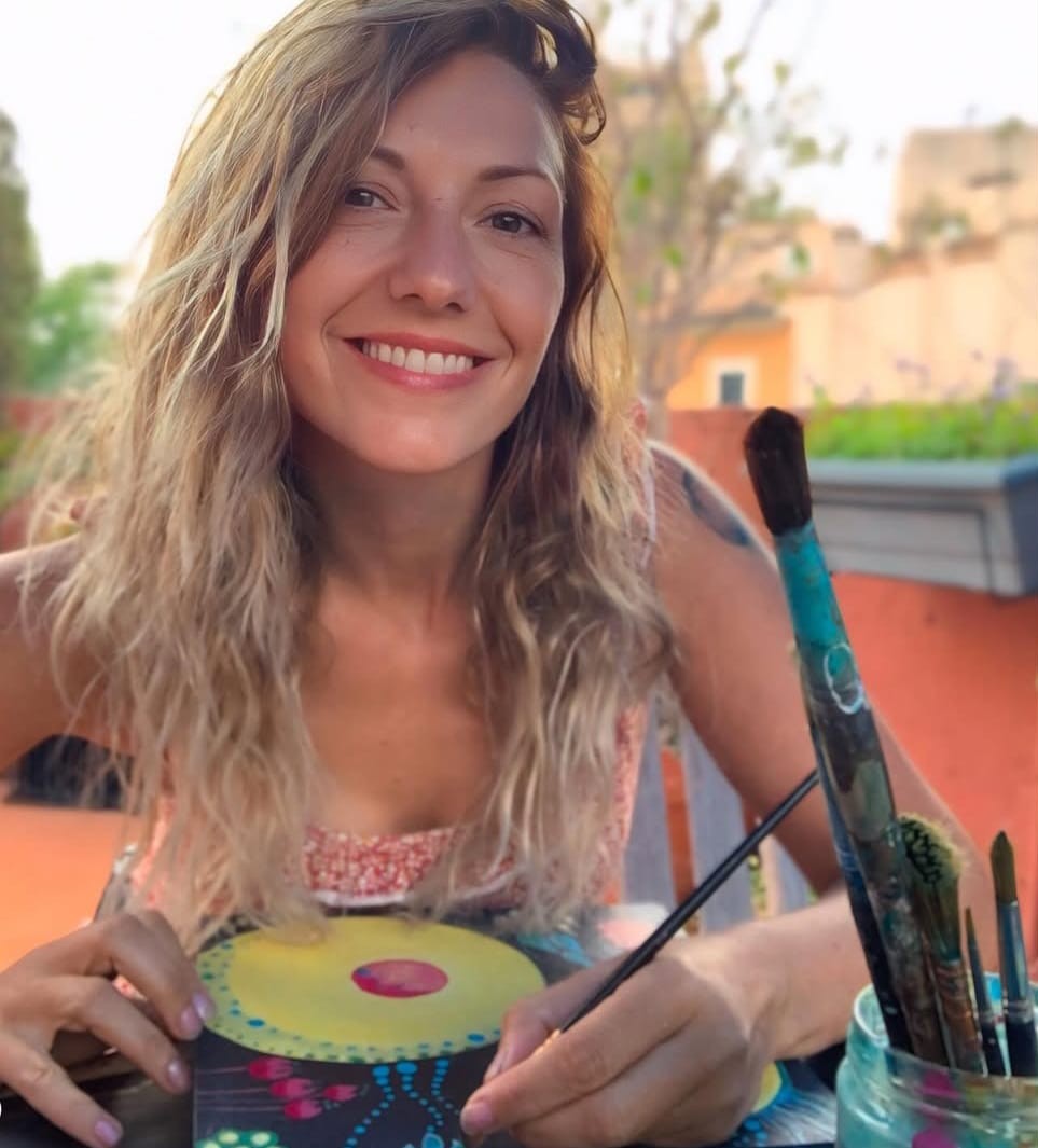 Maite Granados sonriente mientras pinta en su taller al aire libre