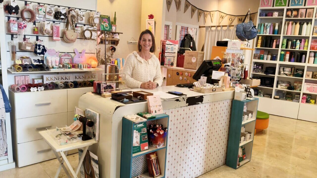 Interior de la tienda Mamy Poppins con productos variados y una mujer sonriente.