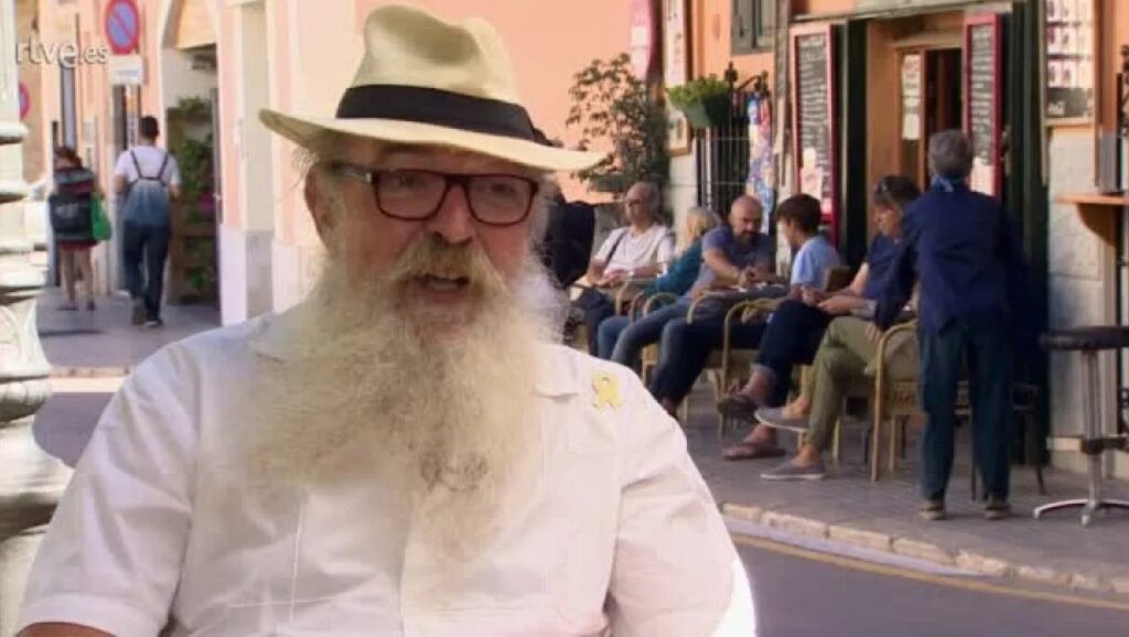 Manel Dom&egrave;nech hablando en una entrevista en la calle con personas al fondo