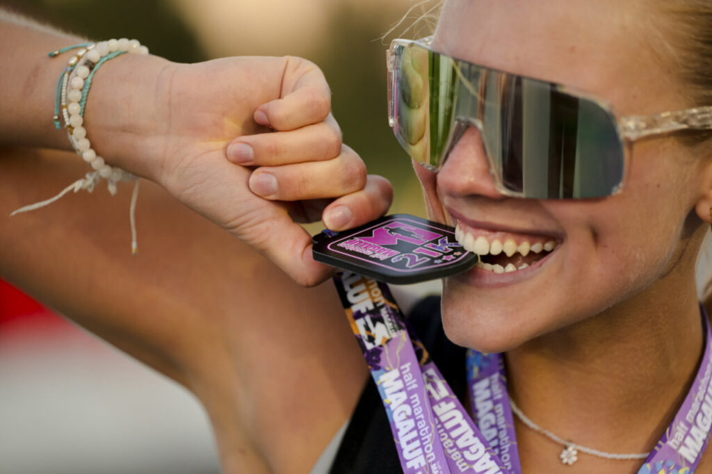 Corredora sonriente sosteniendo su medalla de la Half Marathon Magaluf