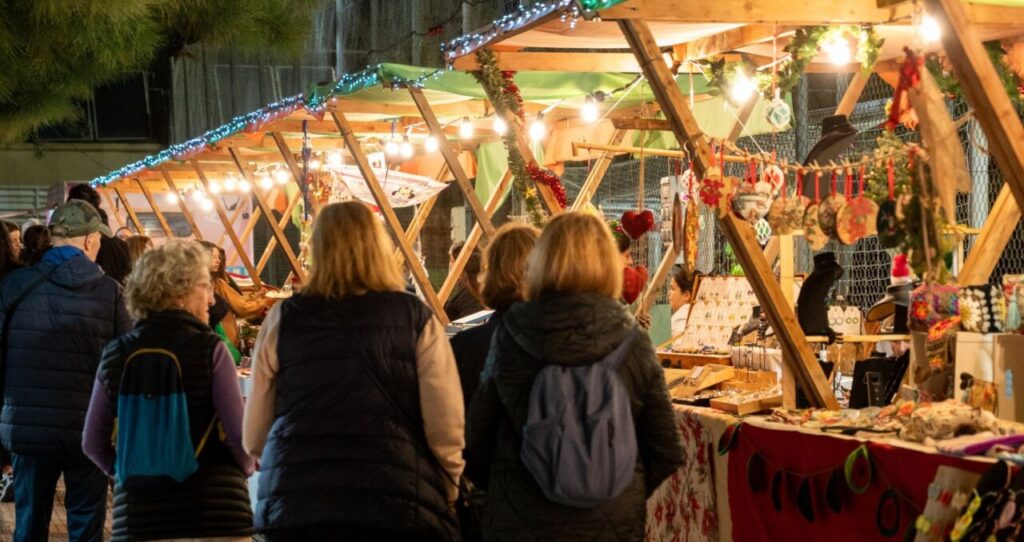 Visitantes en el mercado navideño de Santa Ponça con luces y artesanías.