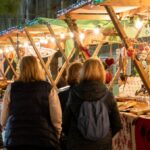 Visitantes en el mercado navideño de Santa Ponça con luces y artesanías.