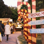 Visitantes en el mercado navideño de Puerto Portals con decoraciones festivas.