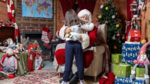 Pap&aacute; Noel abrazando a una ni&ntilde;a en su casita navide&ntilde;a