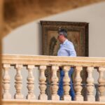 Persona caminando en un balc&oacute;n con barandilla decorativa.