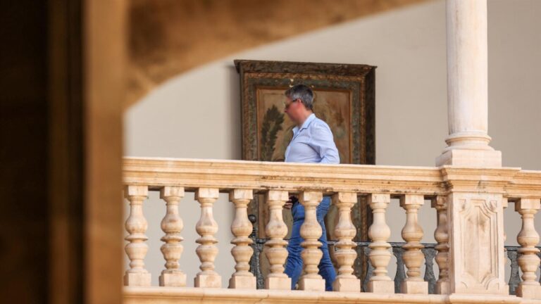 Persona caminando en un balc&oacute;n con barandilla decorativa.