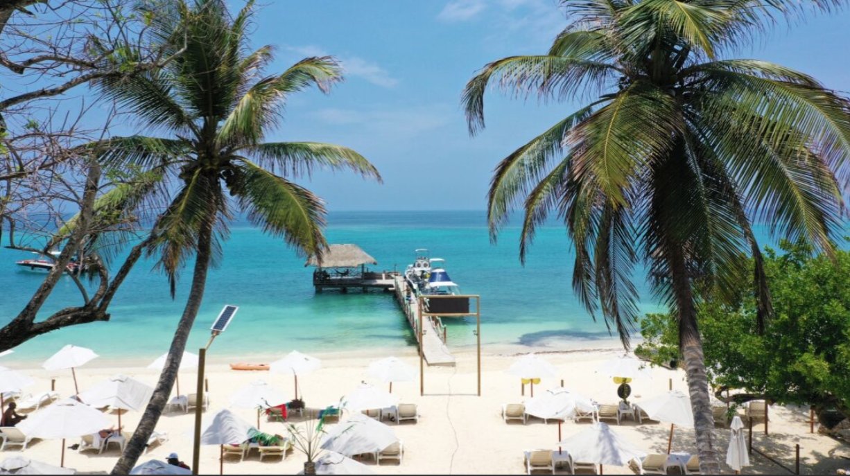 Vista de una playa en Cartagena de Indias con palmeras y muelle