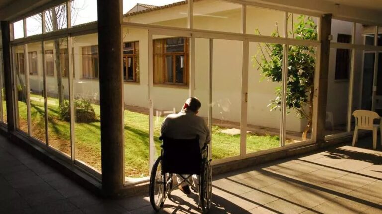 Persona mayor en silla de ruedas en una residencia con jardín