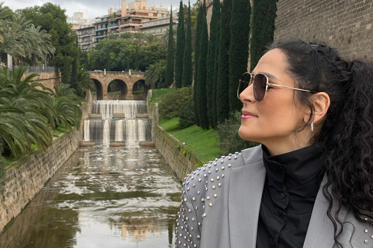 Mujer con gafas de sol junto a una cascada en un parque