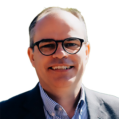 Retrato de un hombre con gafas y chaqueta sonriendo.