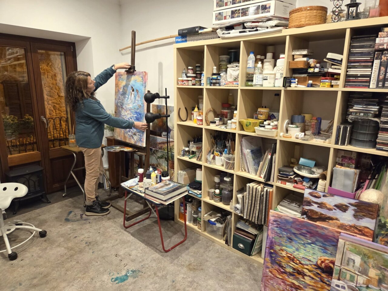 Dolors Martí trabajando en su estudio de arte con pinturas y materiales