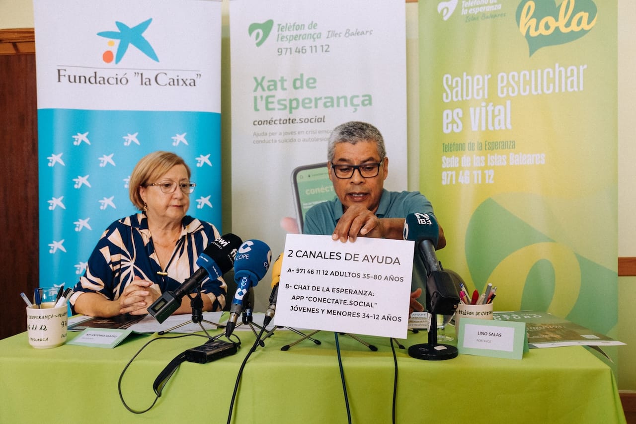 Dos personas presentando información sobre el Teléfono de la Esperanza en Baleares.