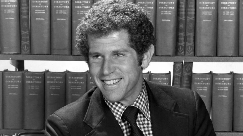 Retrato de Tony Roberts sonriendo frente a estanter&iacute;a de libros