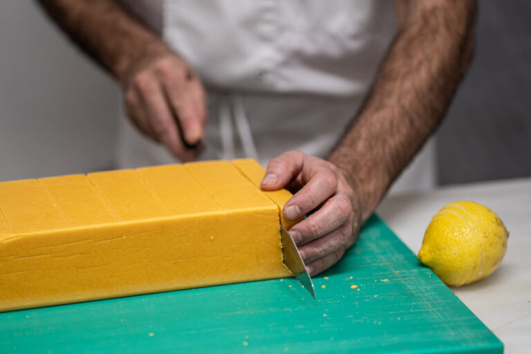 Manos cortando turrón artesano de Mallorca sobre una tabla verde