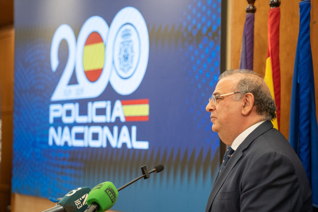 Hombre hablando en el aniversario de la Polic&iacute;a Nacional con un fondo colorido