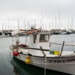Barco de pesca en un puerto con yates al fondo