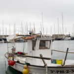 Barco de pesca en un puerto con yates al fondo
