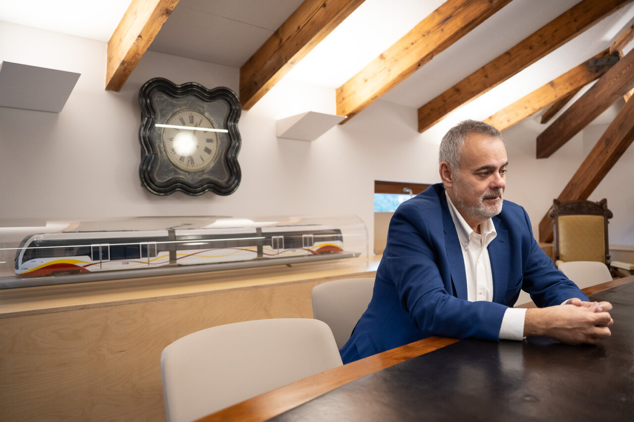 Hombre sentado en una mesa con reloj antiguo y modelo de tren