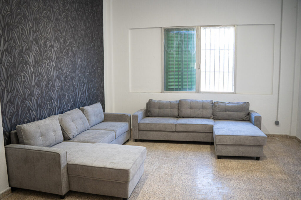 Sala de estar con sof&aacute;s grises en un centro de acogida