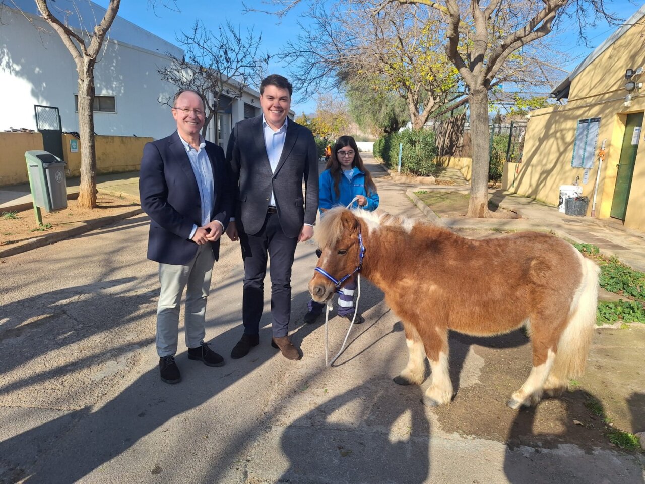 Dos hombres y una mujer junto a un poni en un centro de recuperaci&oacute;n animal