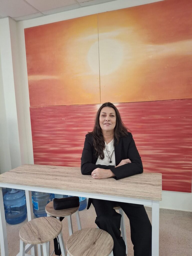 Silvina Barrera sentada en una mesa con fondo art&iacute;stico