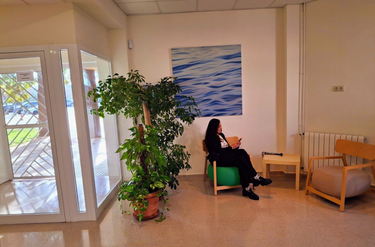 Silvina Barrera sentada en una sala con plantas y una pintura.