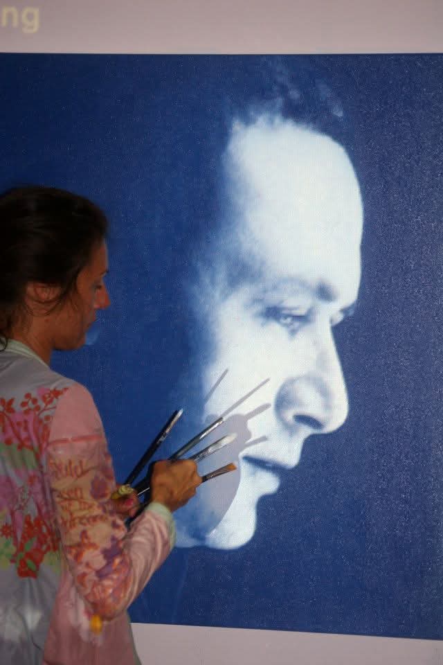 Artista Silvina Barrera pintando un retrato en una exposición