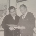 Guillermo Gil revisando un libro con un amigo en una galería de arte