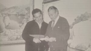 Guillermo Gil revisando un libro con un amigo en una galer&iacute;a de arte